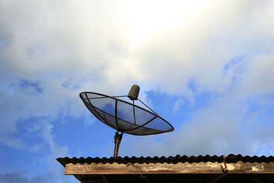 Low angle view of communications tower against cloudy sky