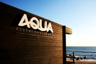 Information sign by sea against clear sky