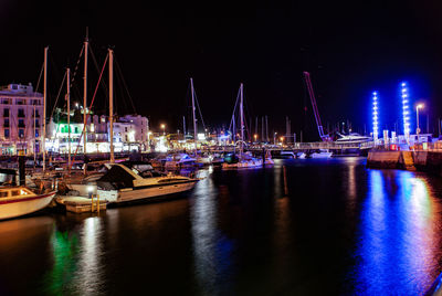 Boats moored at harbor against sky at night