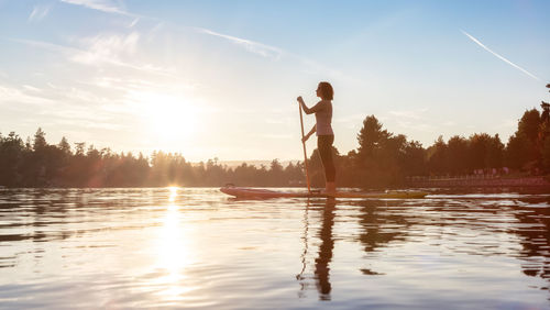 Man standing in lake against sky during sunset