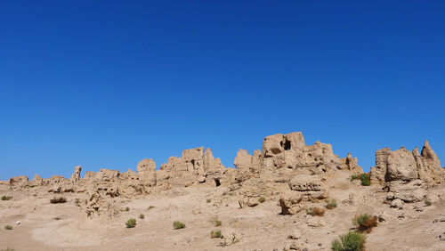 Rock formations on landscape against clear blue sky