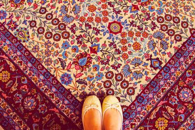 Low section of woman wearing shoes while standing on carpet