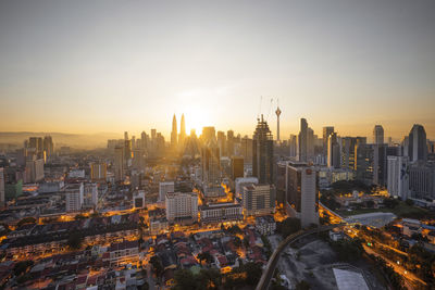 Distant view of petronas towers in city against sky during sunset