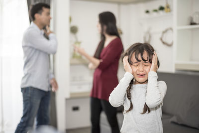 Crying daughter against parents fighting in house