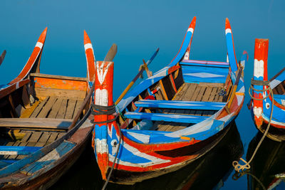 Fishing boats moored at beach against clear blue sky