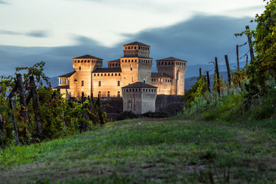 Torrechiara castle against a cloudy sky from grapes of the winery. parma, emilia romagna, italy