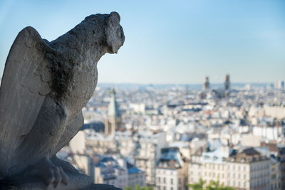 Statue in city against sky