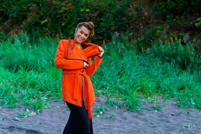 Woman standing against orange wall