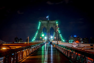 Illuminated brooklyn bridge against sky at night