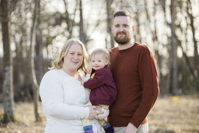 Portrait of happy friends standing against trees