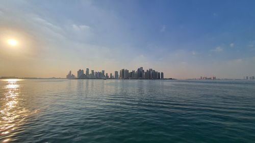 Scenic view of sea by buildings against sky during sunset