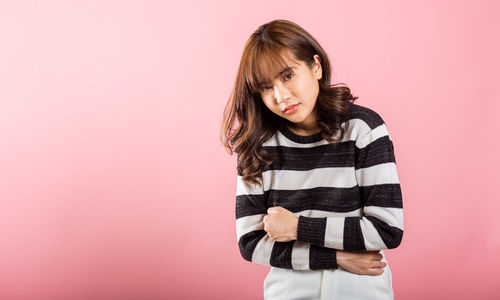 Young woman standing against pink background