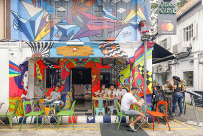 People on chairs against buildings