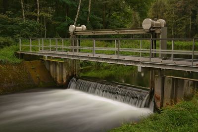 Footbridge over river against trees