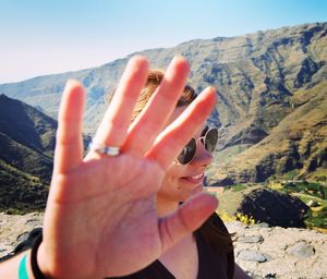 Smiling woman showing hand on mountain during sunny day