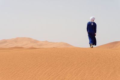 Rear view of man on desert against clear sky