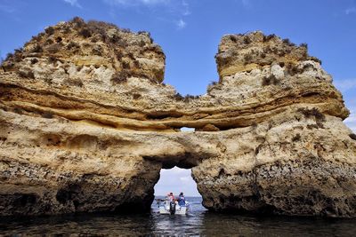 Low angle view of man standing on rock formation against sky
