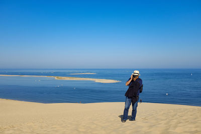 Man photographing at beach against clear sky