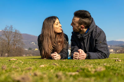 Young couple standing on grass against sky