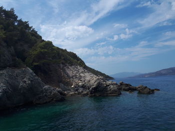 Rock formation by sea against sky