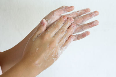 Close-up of hand holding wet leaf against white background