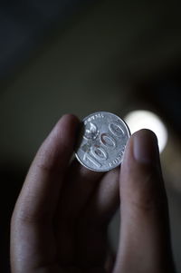 Close-up of hand holding one hundred rupiah coins