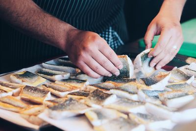 Cropped hands of chef holding fish meat at commercial kitchen