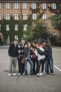 Portrait of smiling male and female friends posing in front of building