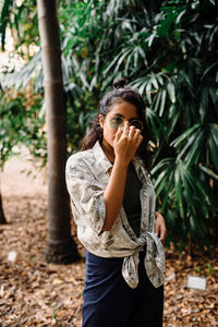 Latina girl with green glasses and green shirt surrounded by leaves