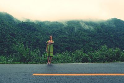 Full length of woman standing on road against mountain during foggy weather