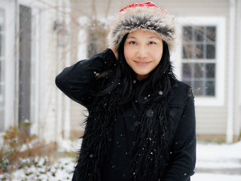 Portrait of smiling young woman during snowfall