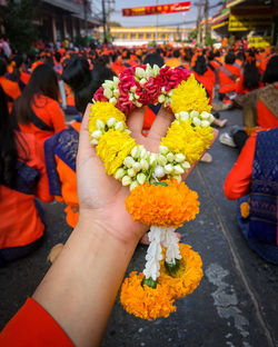 Midsection of people holding flowering plant in city