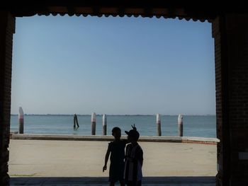Rear view of people looking at sea against clear sky
