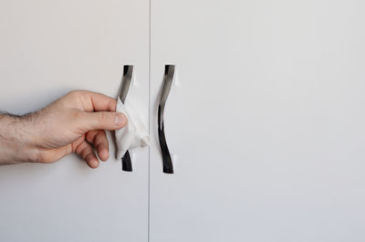 Close-up of hand holding paper over white background