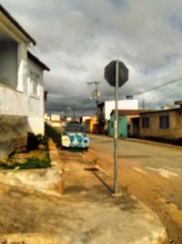 Cars on street by buildings against sky