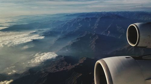 Cropped image of airplane flying over mountains