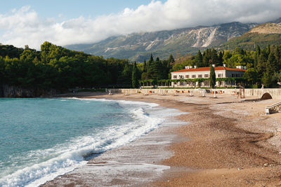 Scenic view of beach by mountains against sky