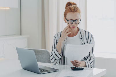 Woman using phone while sitting on table