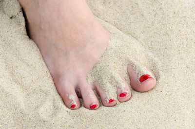 Low section of woman with painted toenails on sand