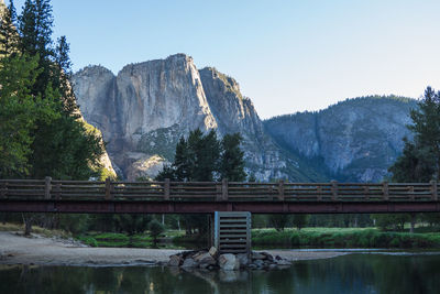 Bridge over river by mountains against sky