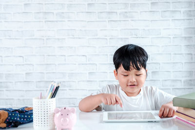 Portrait of boy holding mobile phone on table