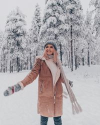 Woman standing against snow covered trees