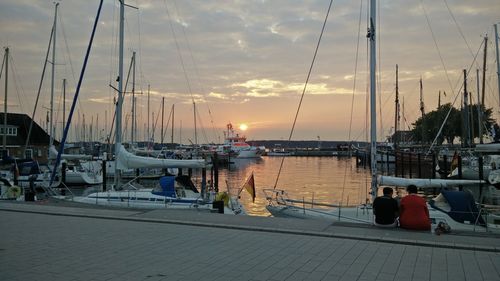 Boats moored at harbor against sky during sunset