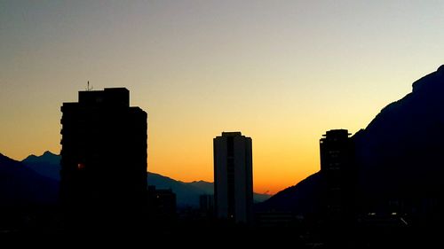 Silhouette buildings against clear sky at sunset