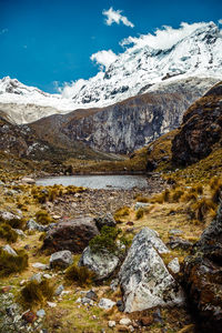 Scenic view of stream by snowcapped mountains against sky