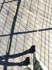 Low section of woman standing on boardwalk during sunny day