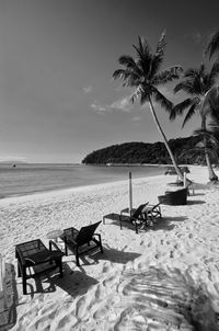 Chairs on beach by sea against sky