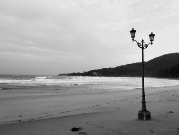 Street light on beach against sky