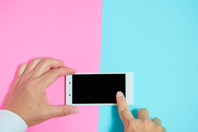 Close-up of person using mobile phone over colored background