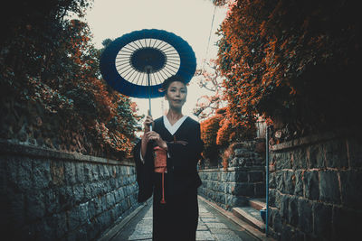 Woman standing on footpath amidst buildings